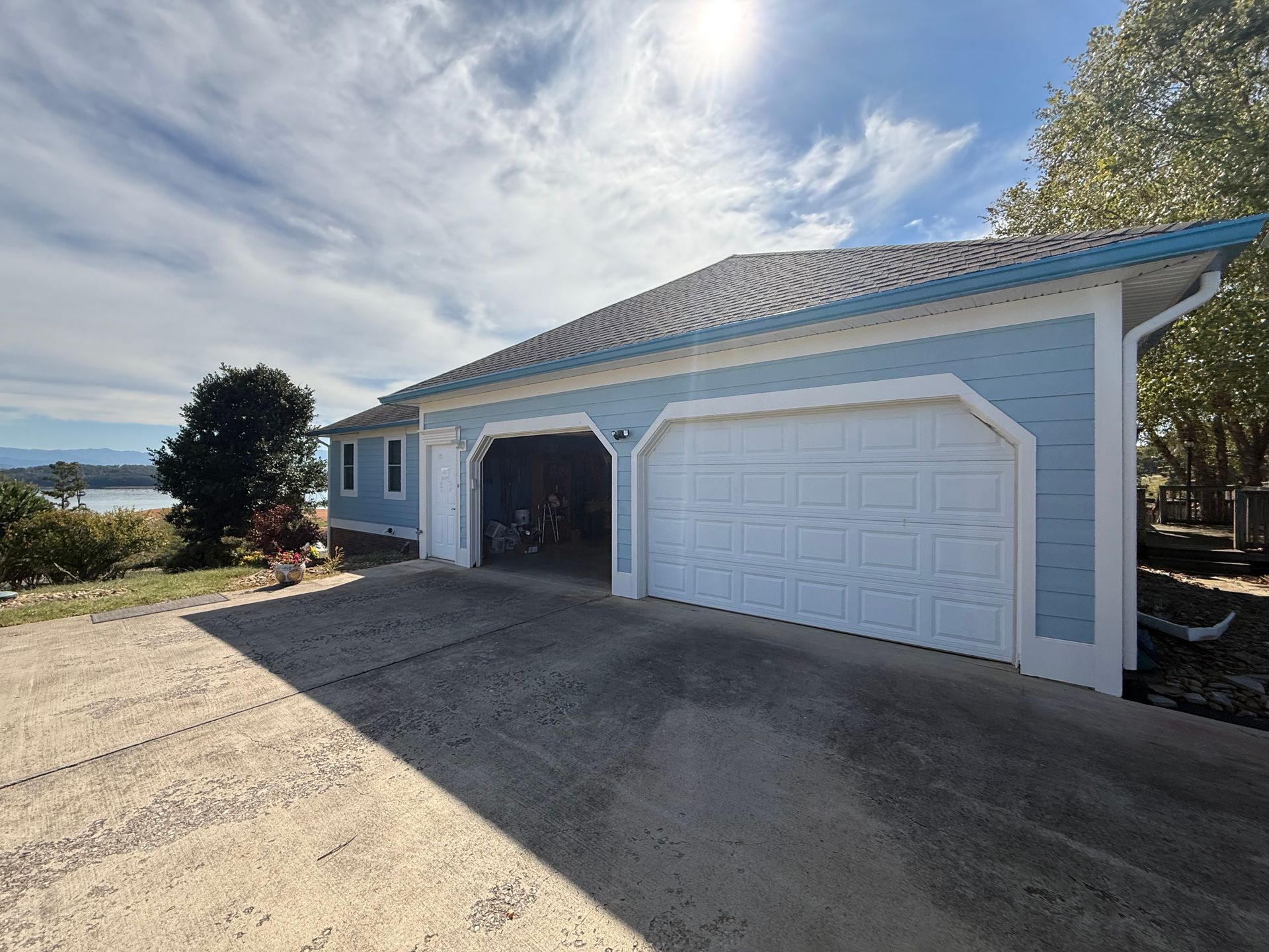 Light blue garage with white doors under a sunny sky.