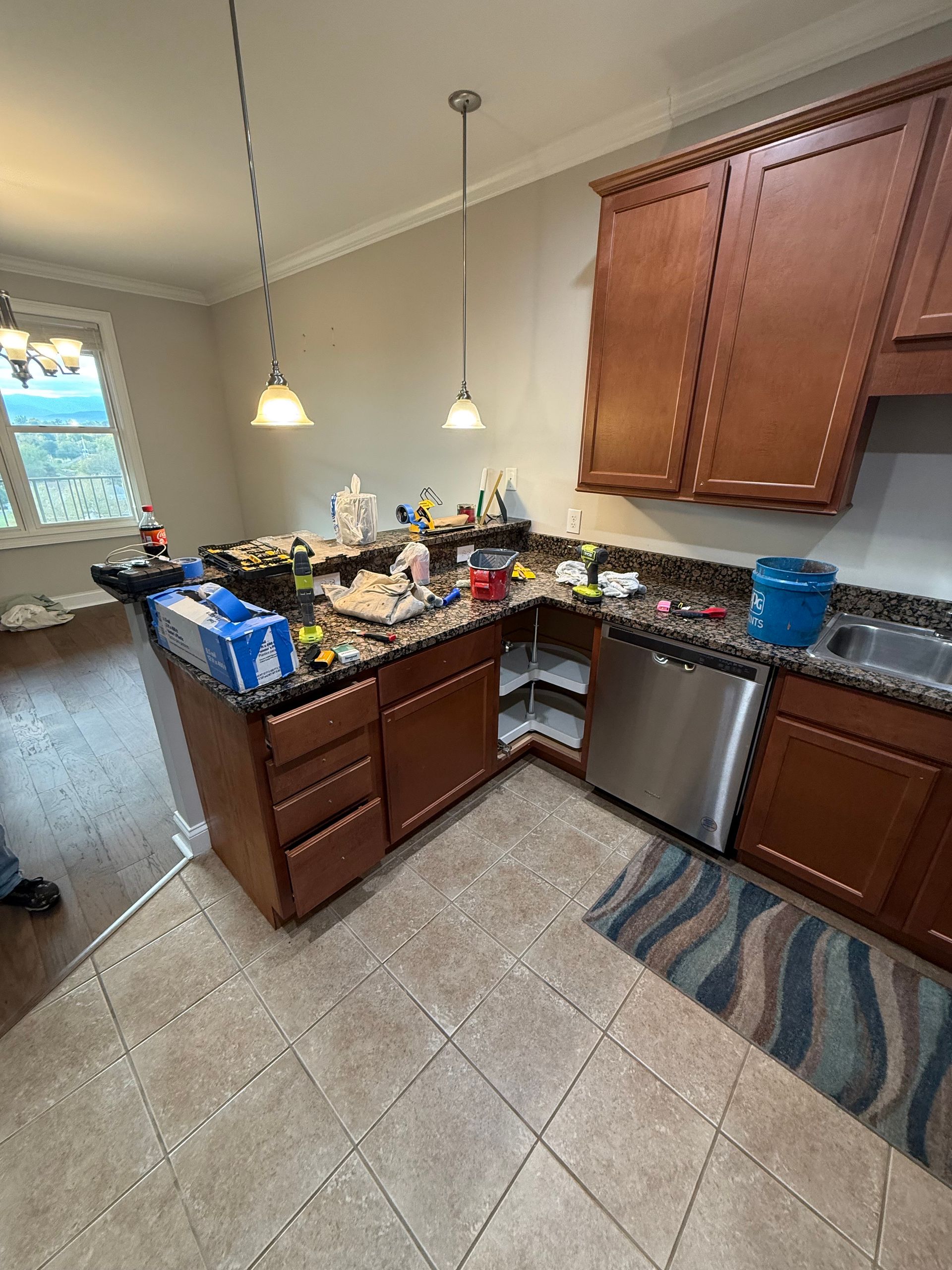 Kitchen with brown cabinets, granite countertops, and stainless steel appliances. Construction materials are on the counter.