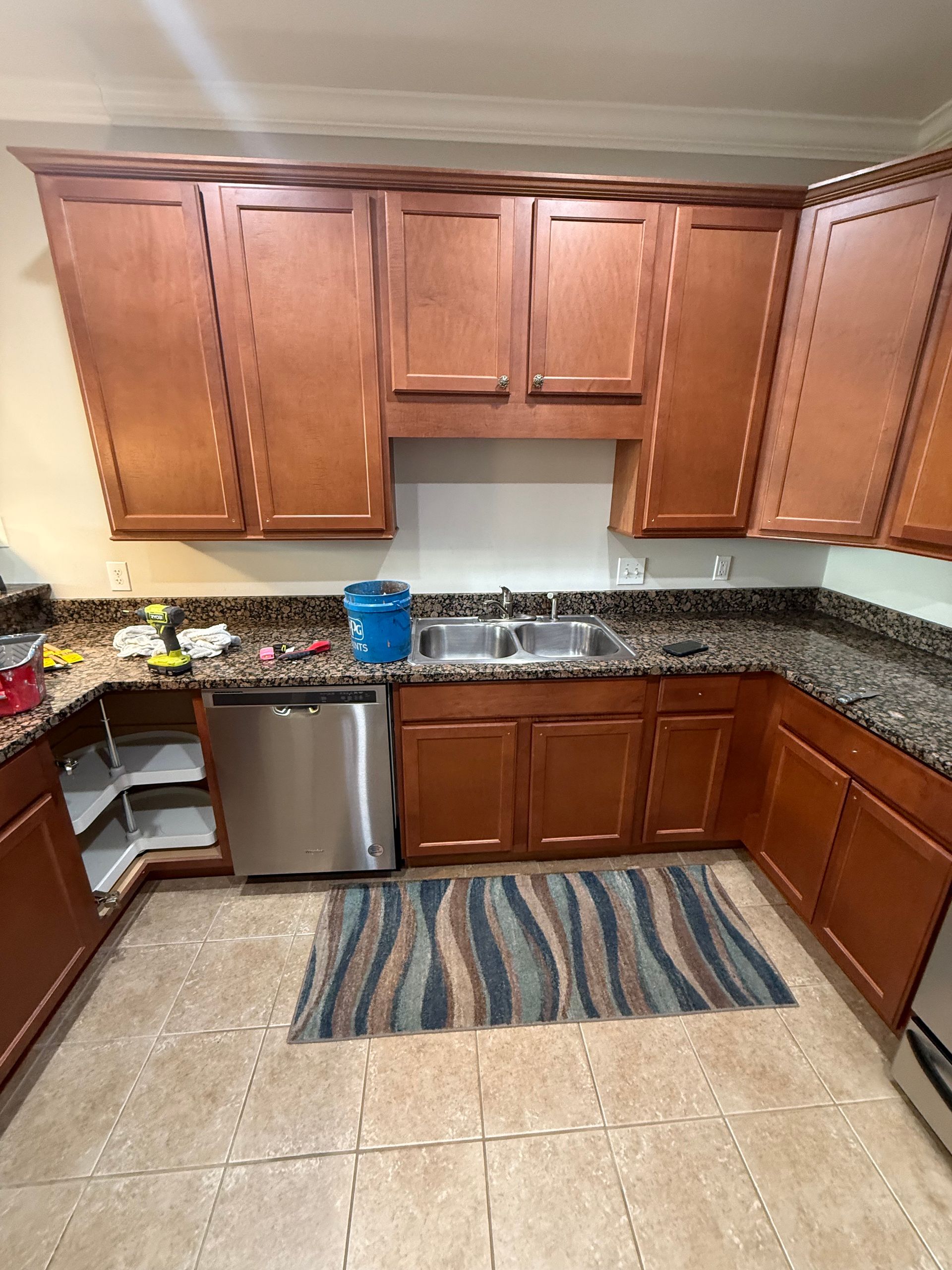 Kitchen with wood cabinets, stainless steel appliances, and granite countertops. A blue rug is in front of the sink.