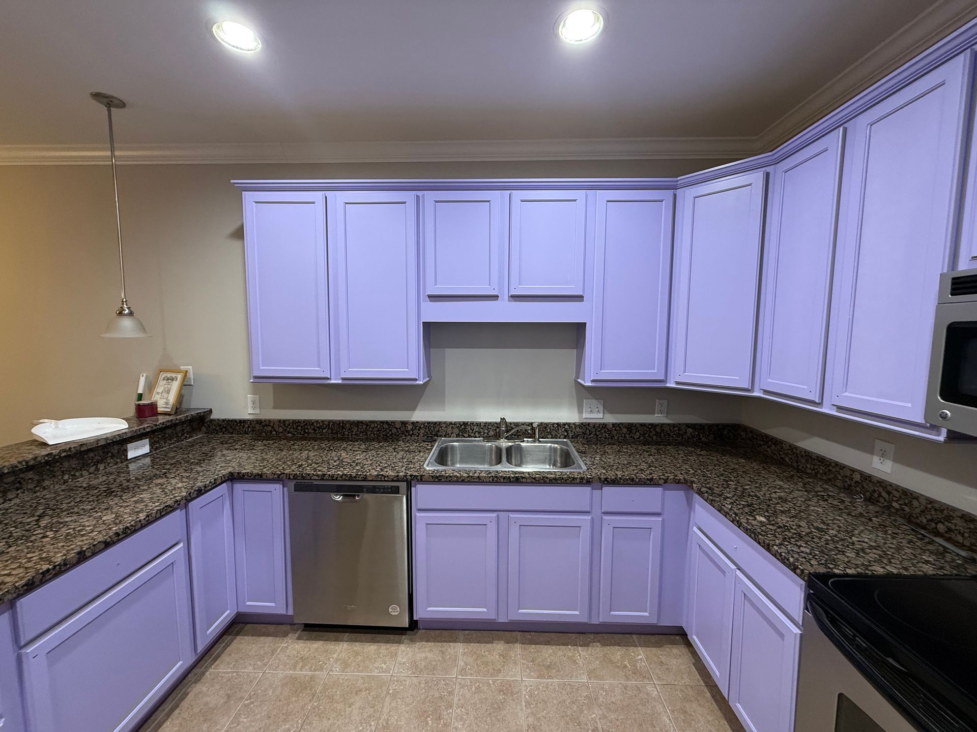 Purple kitchen cabinets, granite countertops, stainless steel appliances in a bright kitchen.