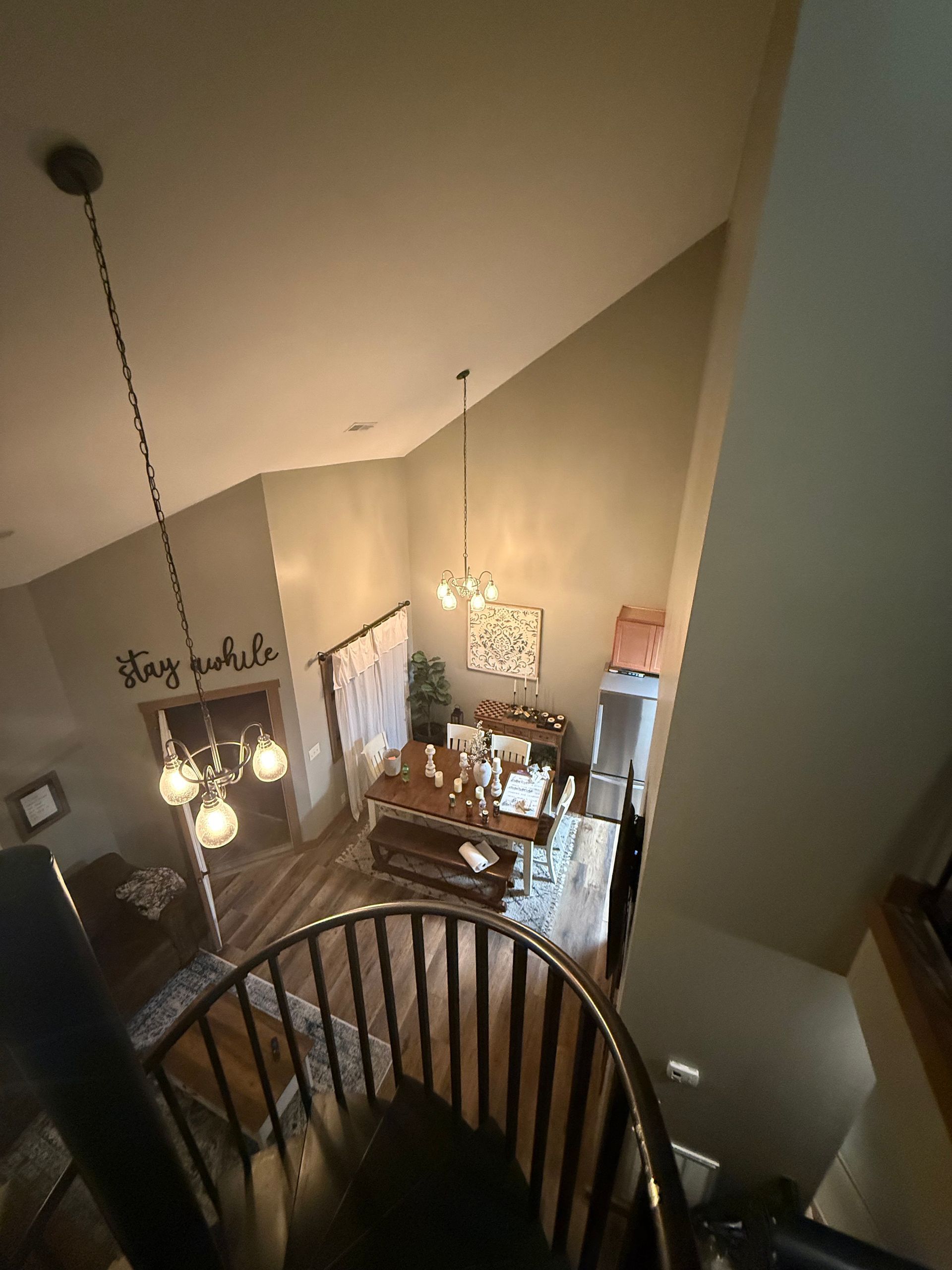 View from above of a dining area with a long table, chairs, and two chandeliers.