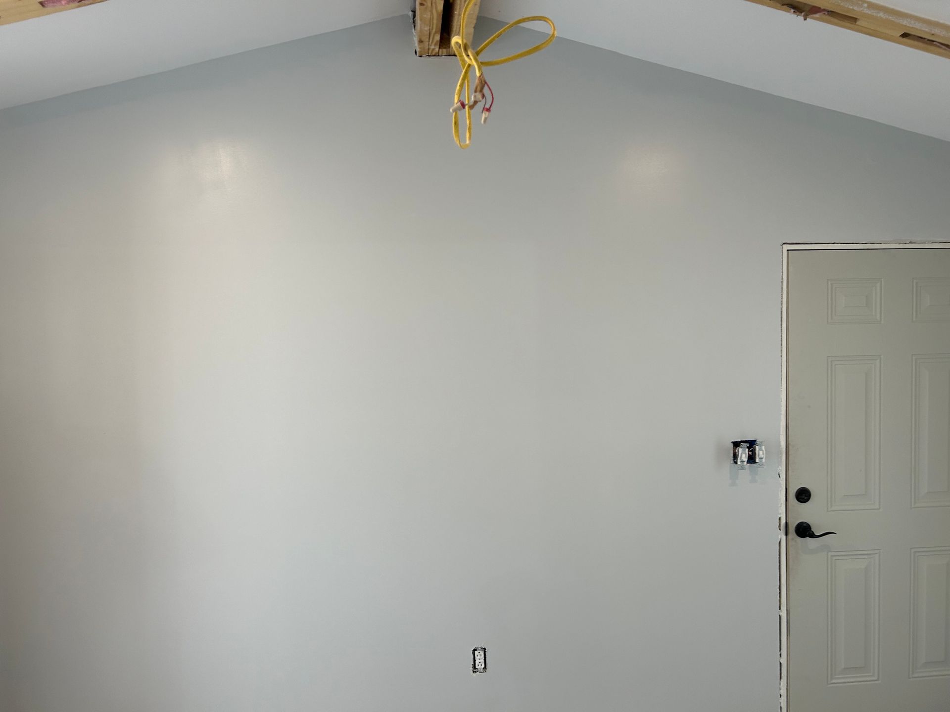 Interior wall painted light blue with door, electrical box, and exposed wires.