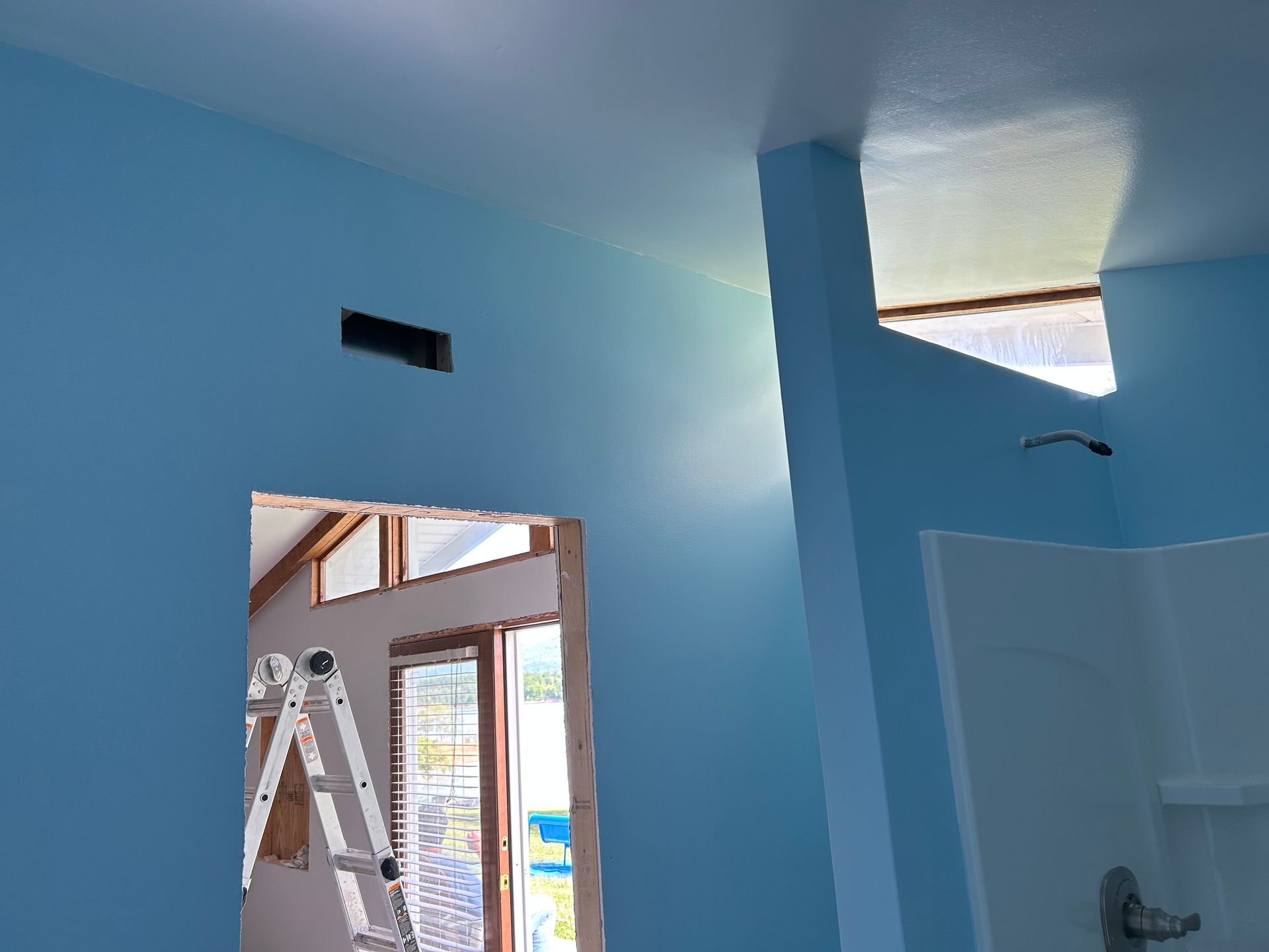 A person is painting a wall with a paint roller.