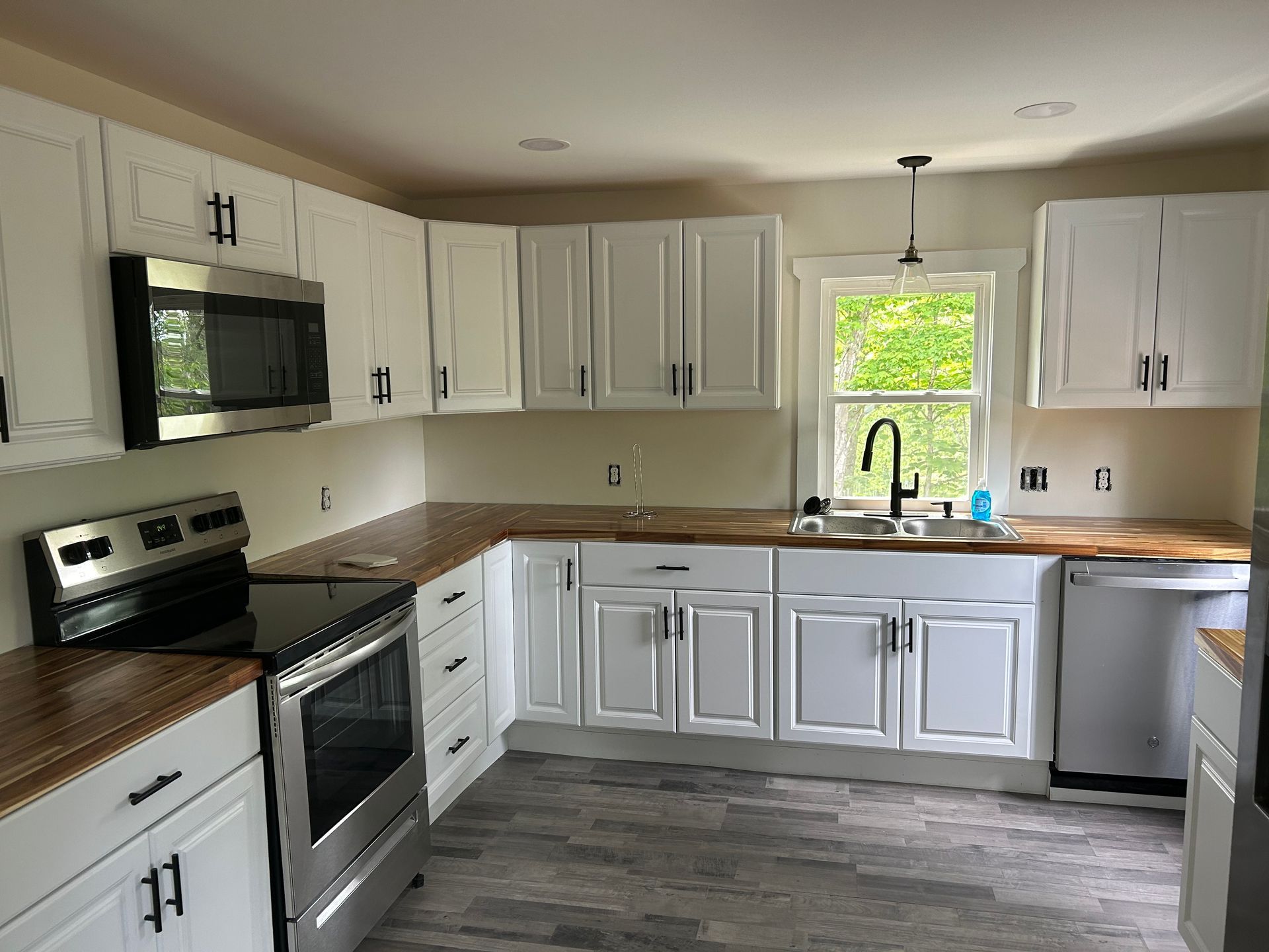 A kitchen with white cabinets and stainless steel appliances and a large island.