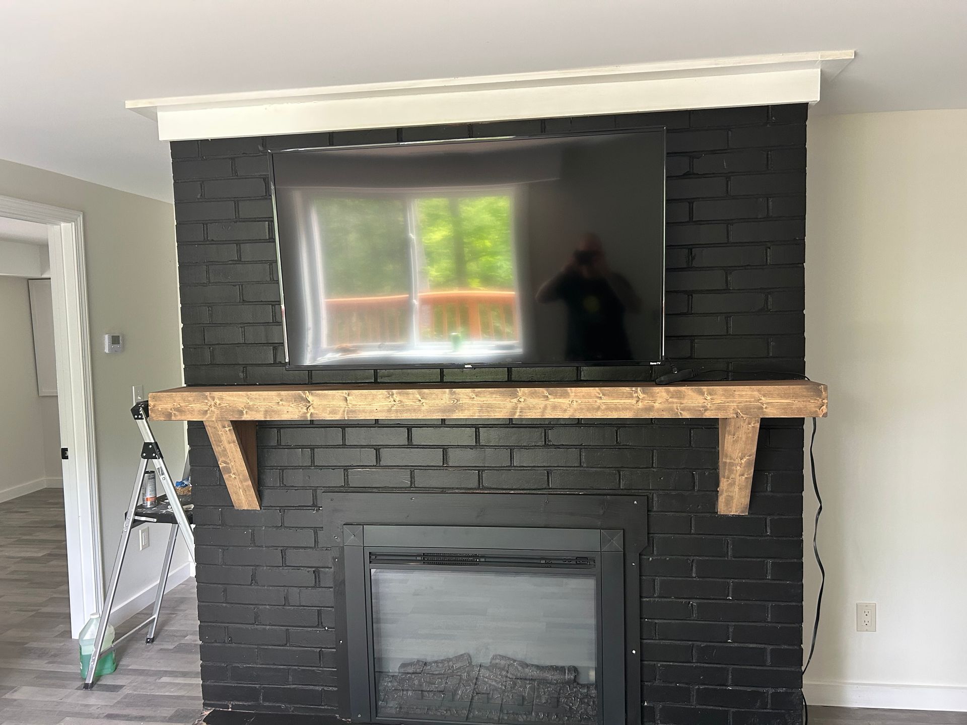 Black brick fireplace with a mounted TV, a wooden mantel, and a white header.