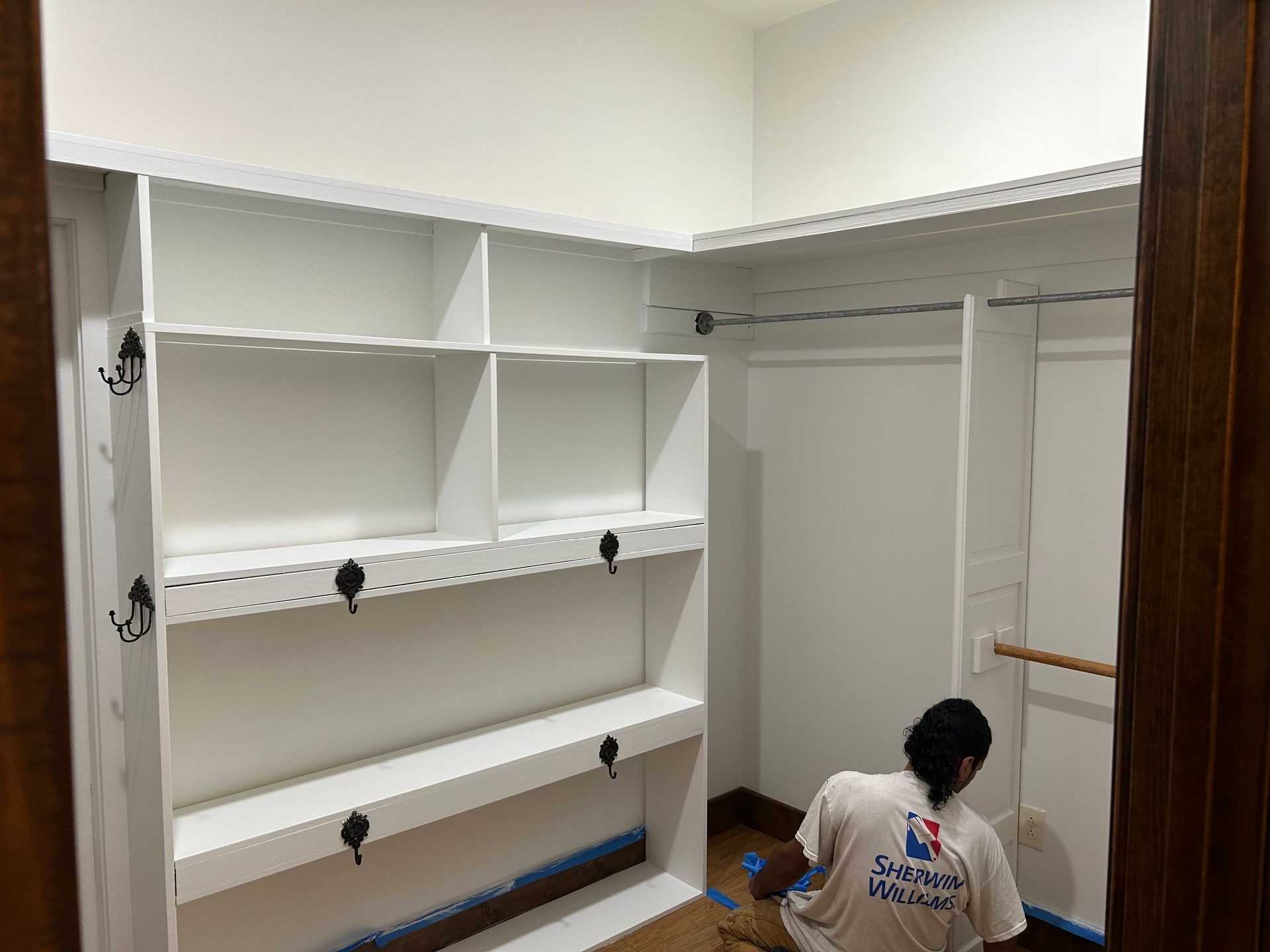 A man is painting a closet in a house.