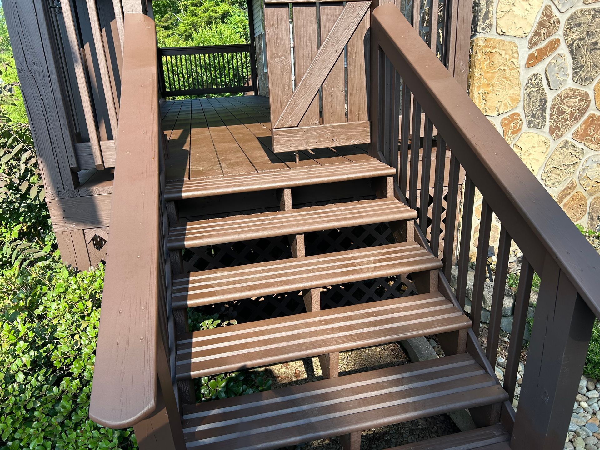 Wooden outdoor staircase leading to a small deck with a brown gate. The steps are painted brown.
