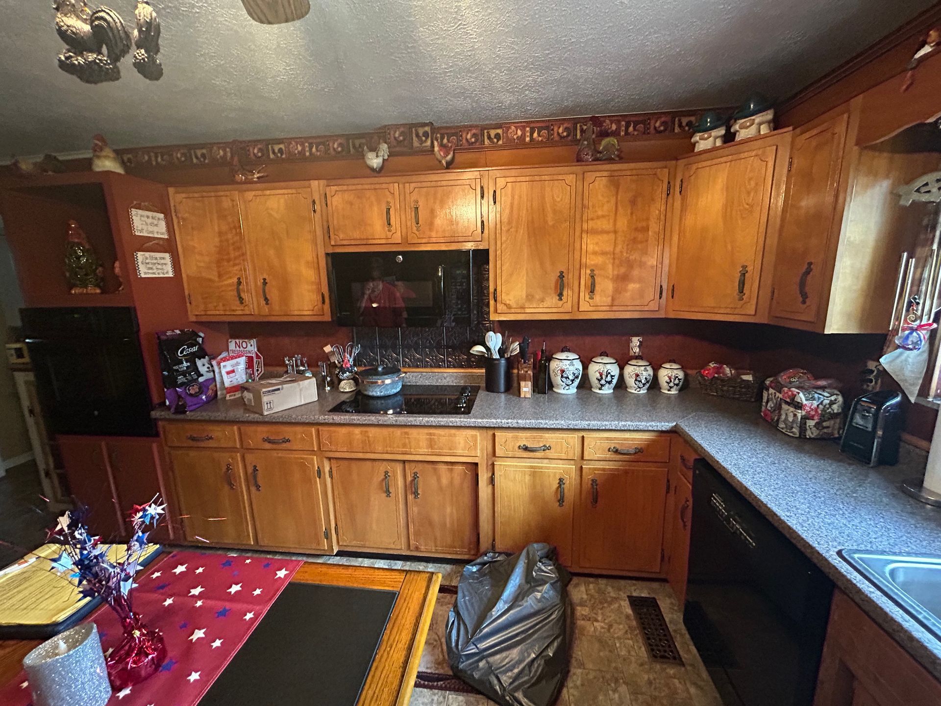 Kitchen with wooden cabinets, countertop, and appliances. A trash bag sits on the floor.