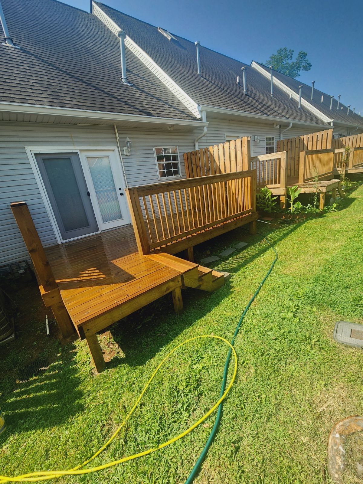 Wooden decks attached to a row of houses; green grass, bright sunlight.