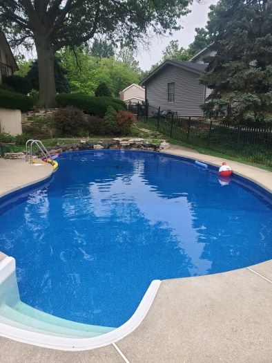 A large swimming pool in a backyard with a house in the background.