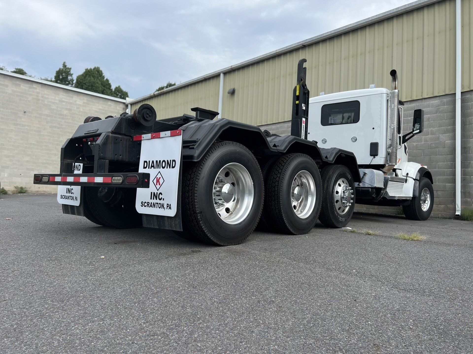 A white dump truck is parked in front of a building.