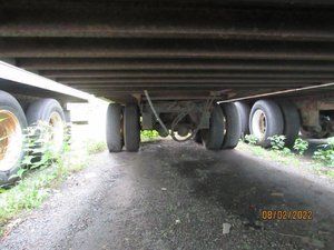 A truck is parked under a bridge on a dirt road.