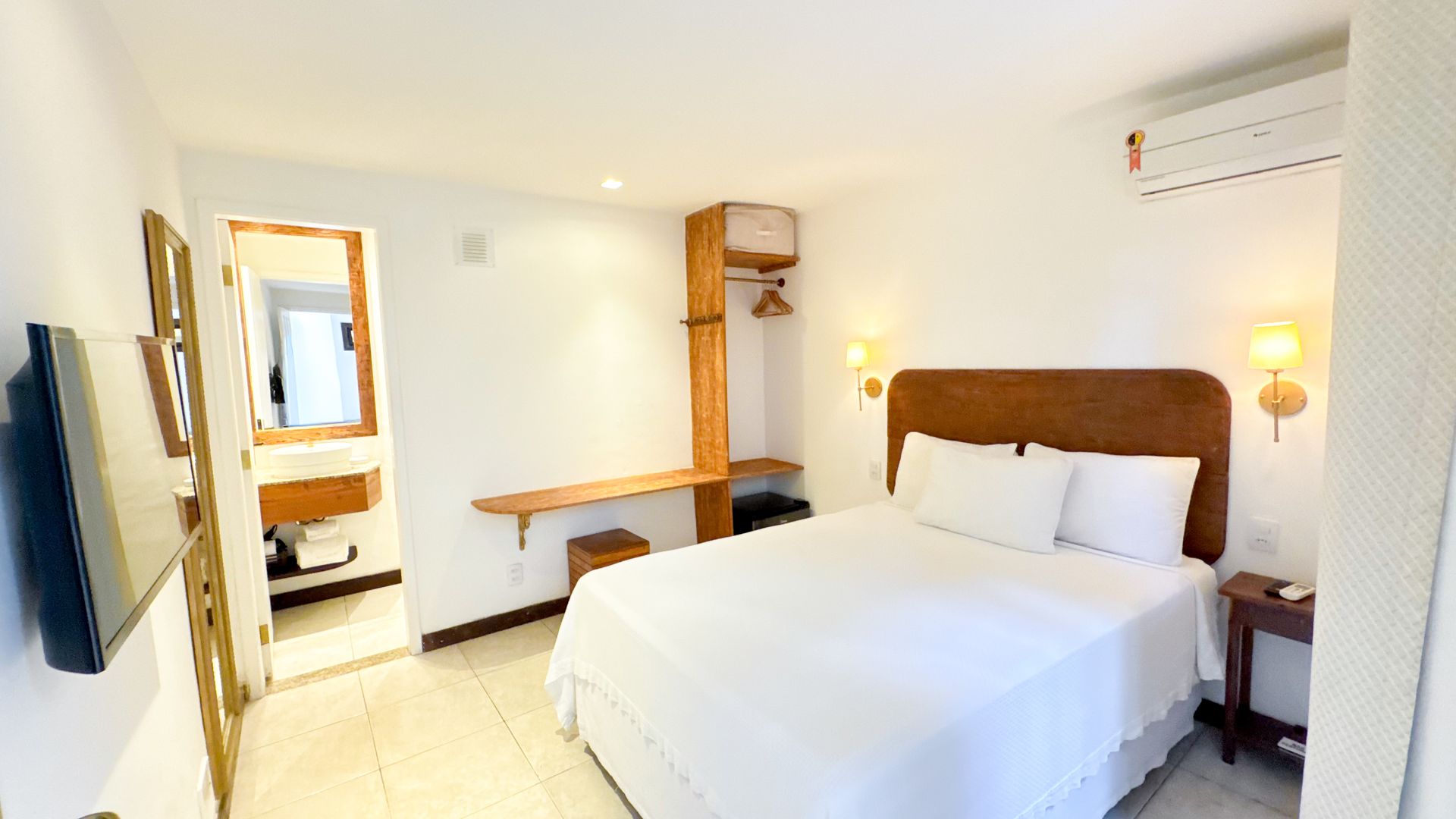 Hotel room with a bed, desk, open closet, and attached bathroom.