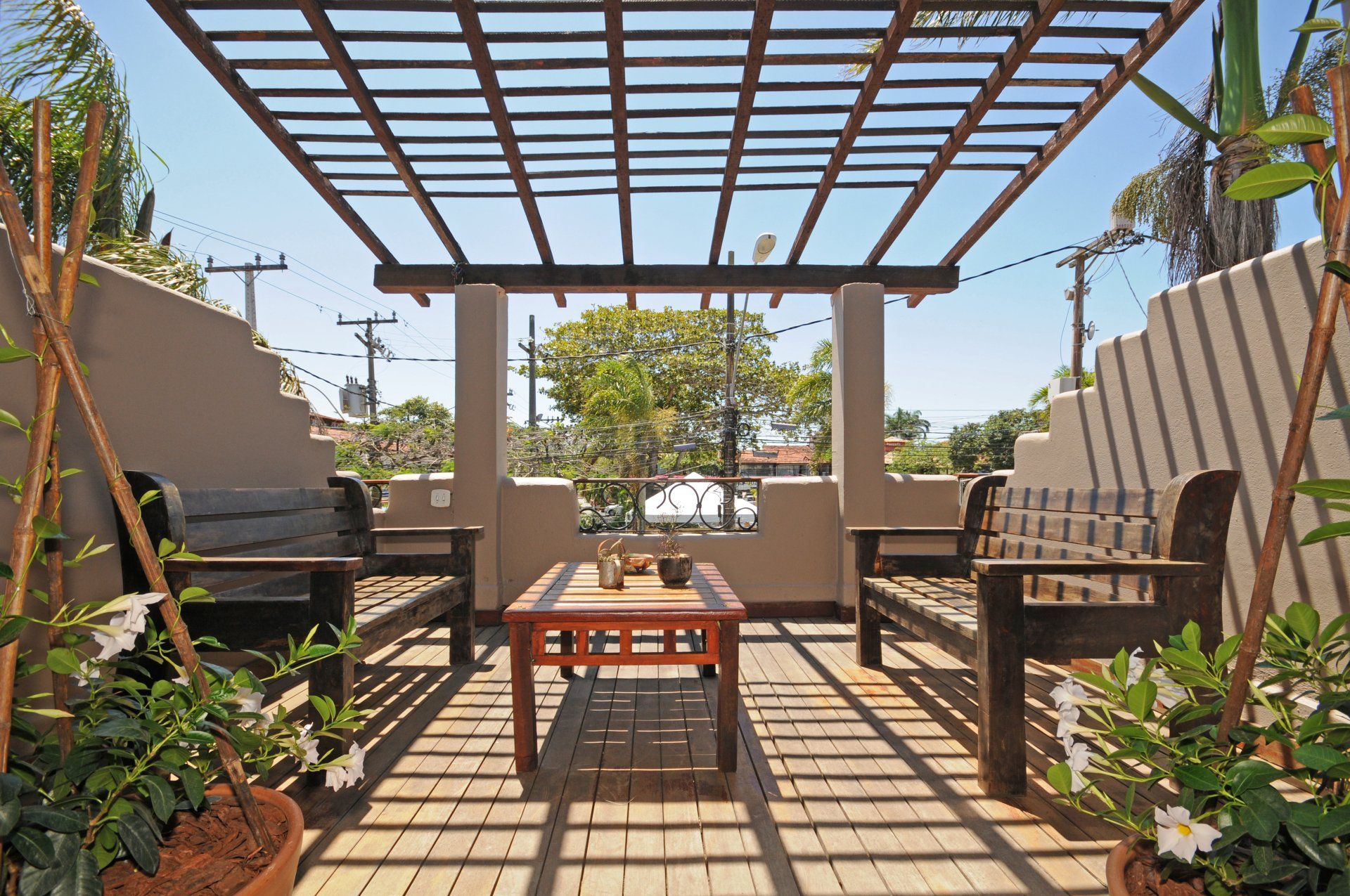 Outdoor patio with wood pergola, benches, and table; potted plants on either side.