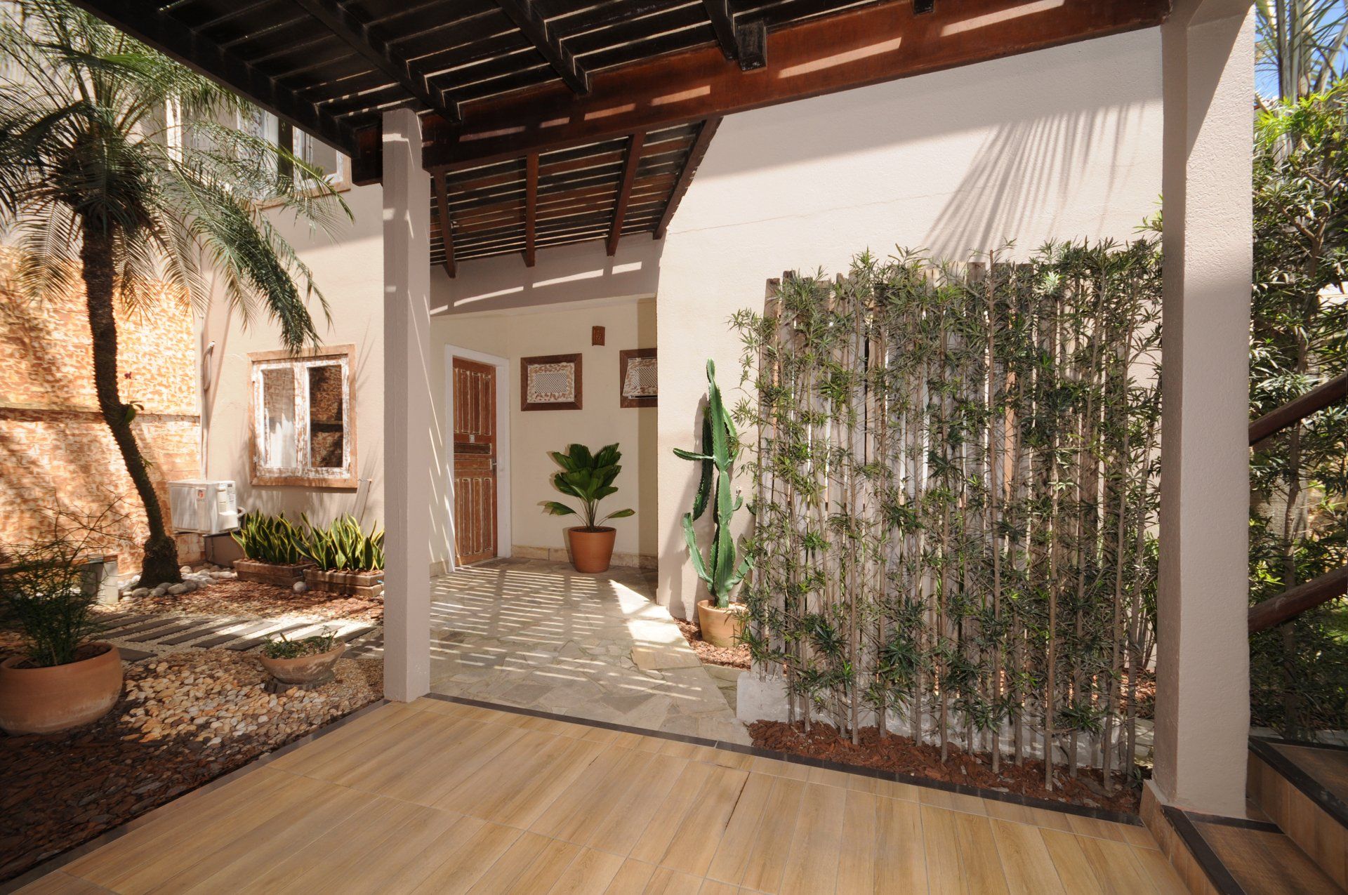 Outdoor patio with wooden deck, trellis, and green wall; leads to interior doorway.