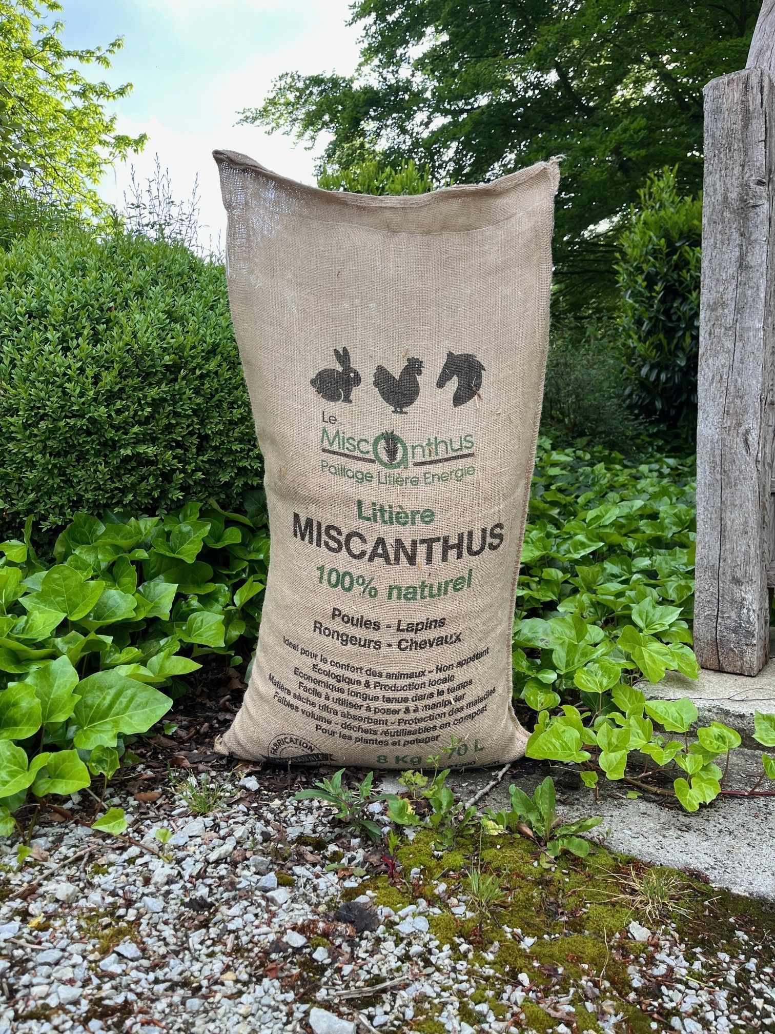 Un grand sac en toile de jute est posé au sommet d'une route de gravier.