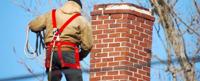 A man is standing on top of a brick chimney.