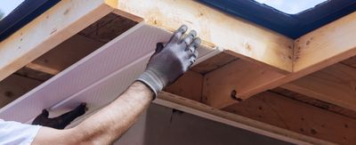 A man wearing gloves is working on a roof.