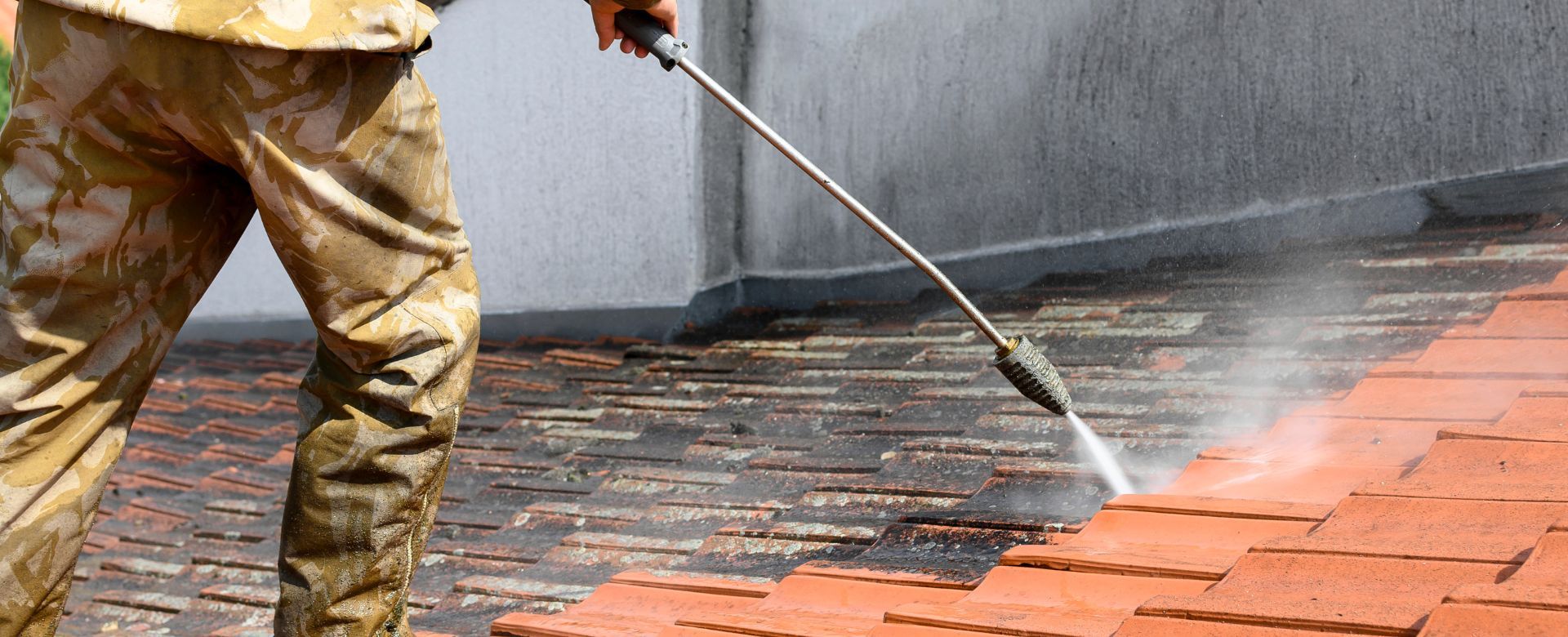 A man is using a high pressure washer to clean a brick walkway.