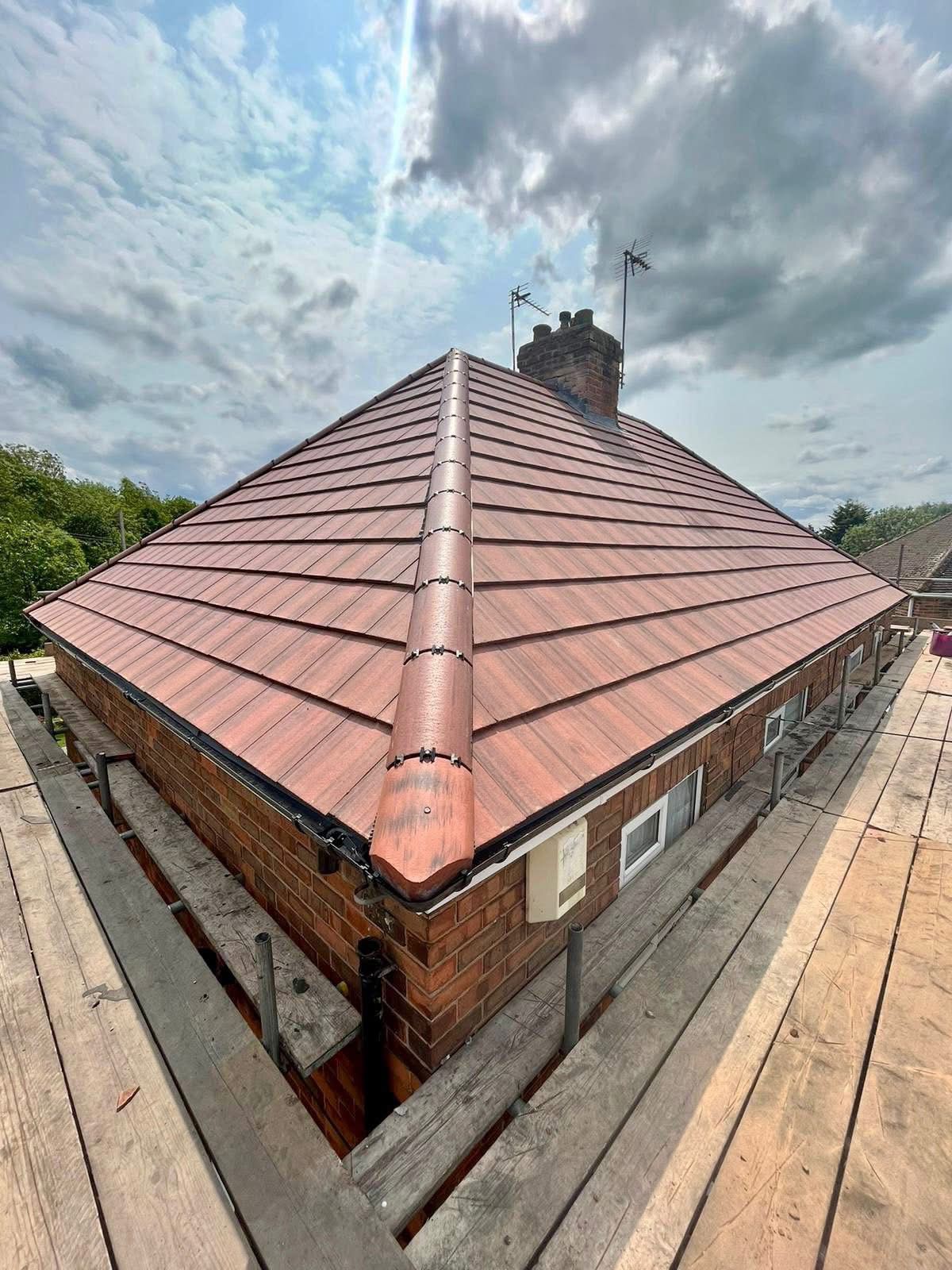 A brick house with a red tiled roof is sitting on top of a wooden scaffolding.