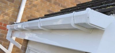 A close up of a gutter on the side of a house.
