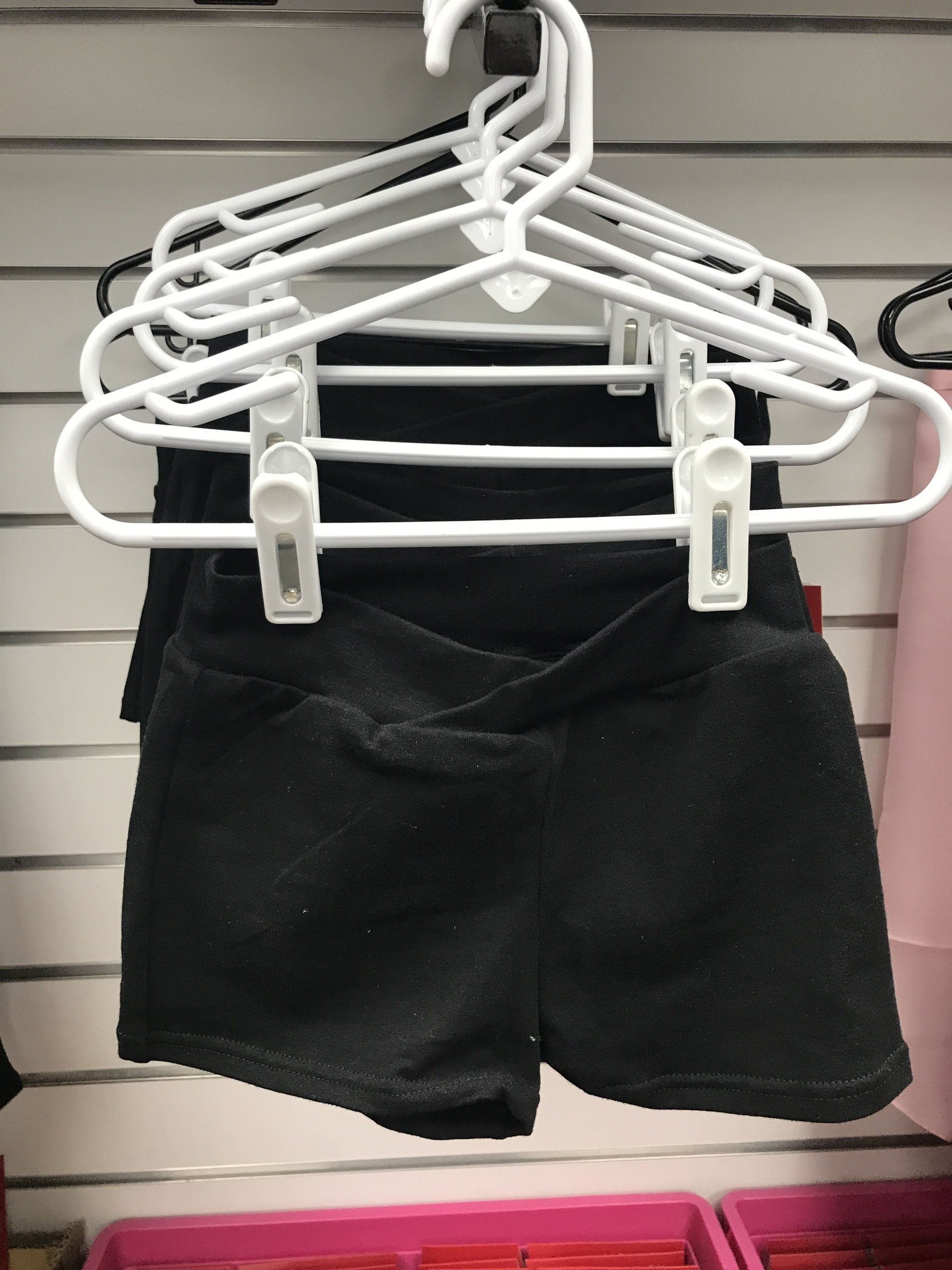 A pair of black shorts hanging on a white hanger