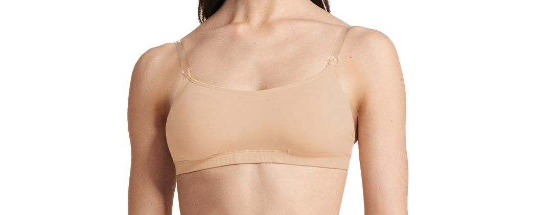 A woman in a tan bra is standing on a white background.