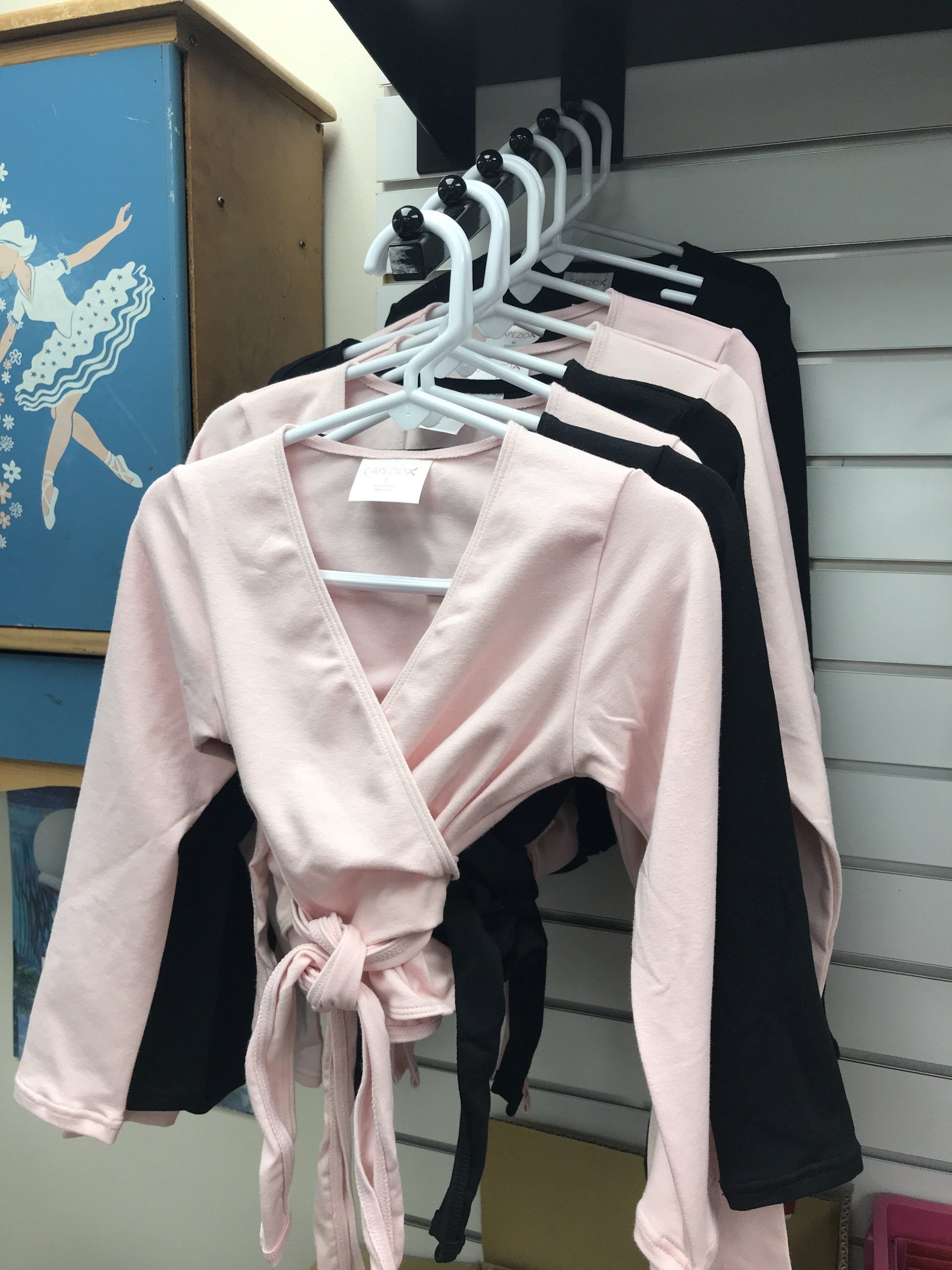A row of pink and black shirts are hanging on a rack