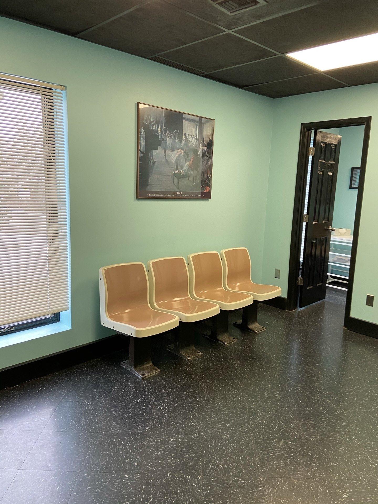 A waiting room with a row of chairs and a picture on the wall.