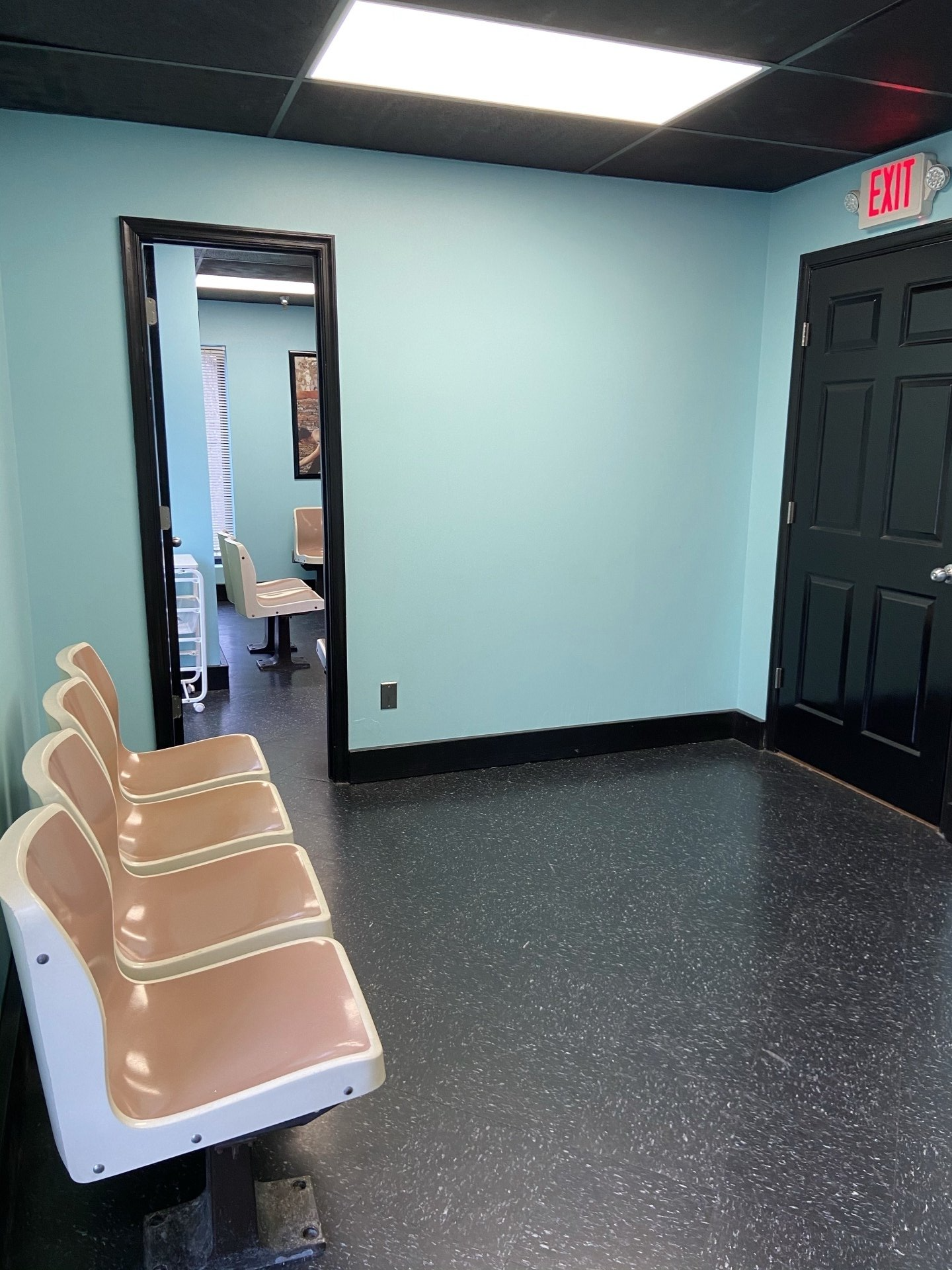 A waiting room with a row of chairs and a door.