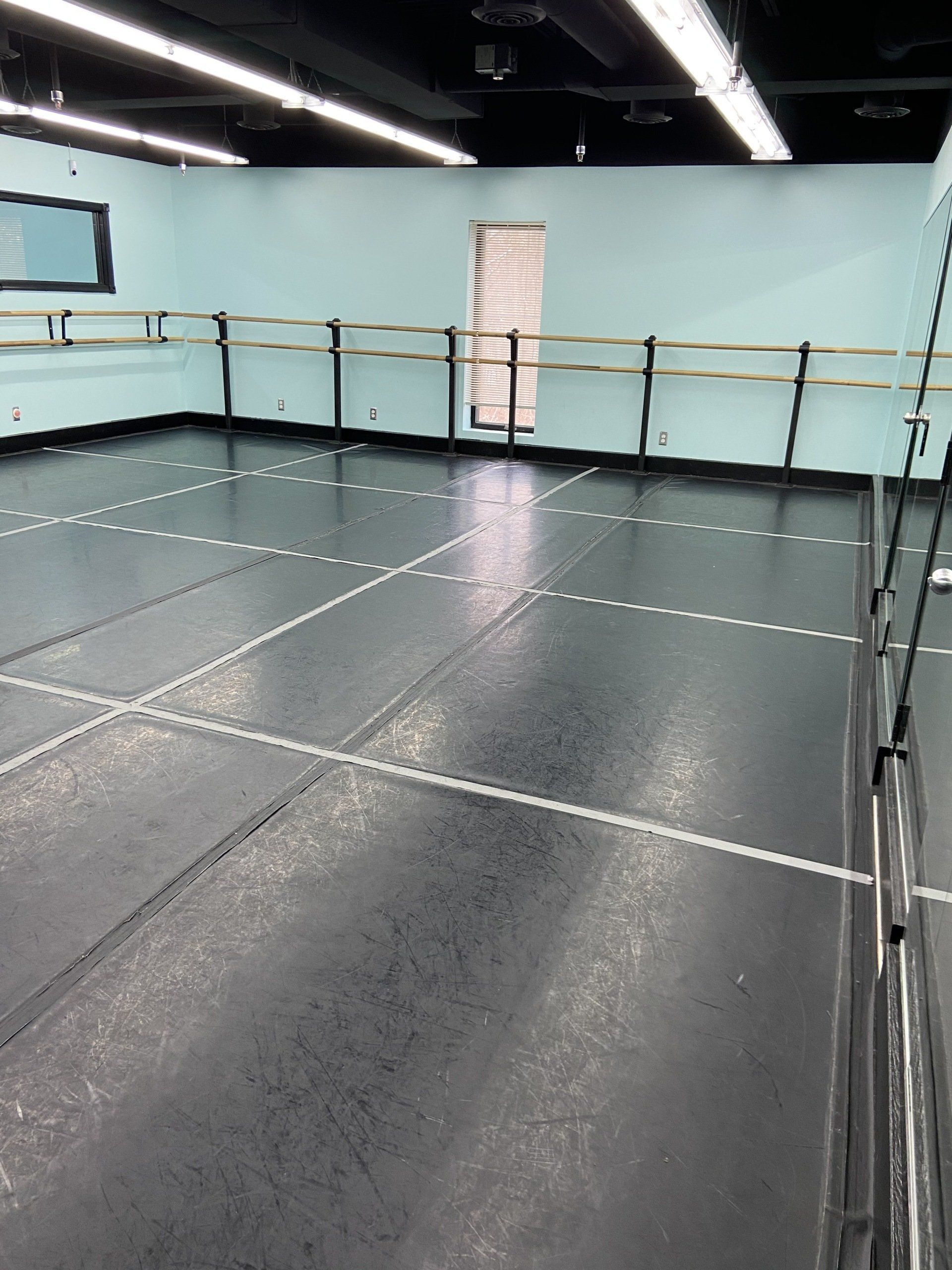 An empty dance studio with a black floor and blue walls