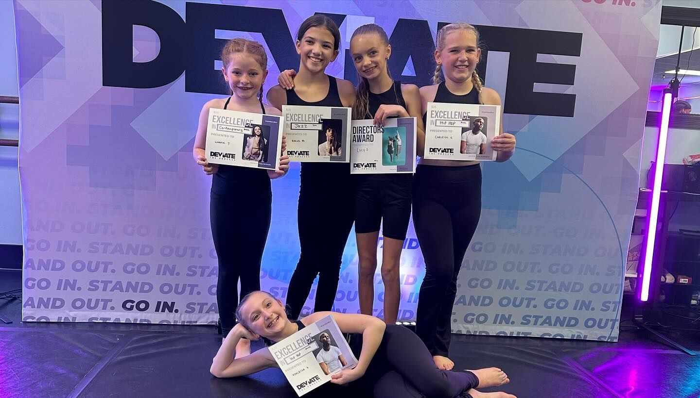 A group of young girls are posing for a picture while holding certificates.
