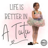 A little girl in a tutu is standing next to a sign that says `` life is better in a tutu ''.
