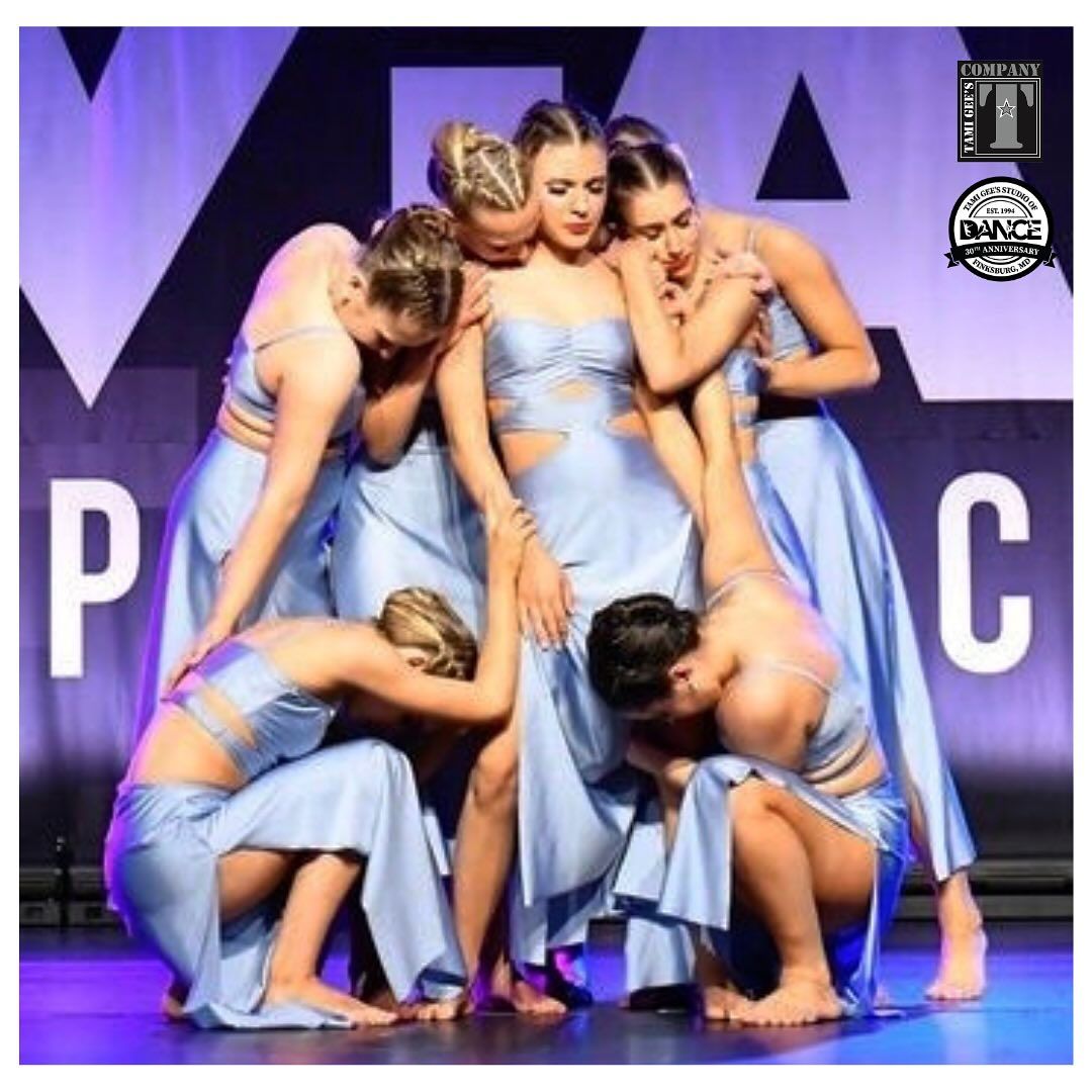 A group of women in blue dresses are posing for a photo