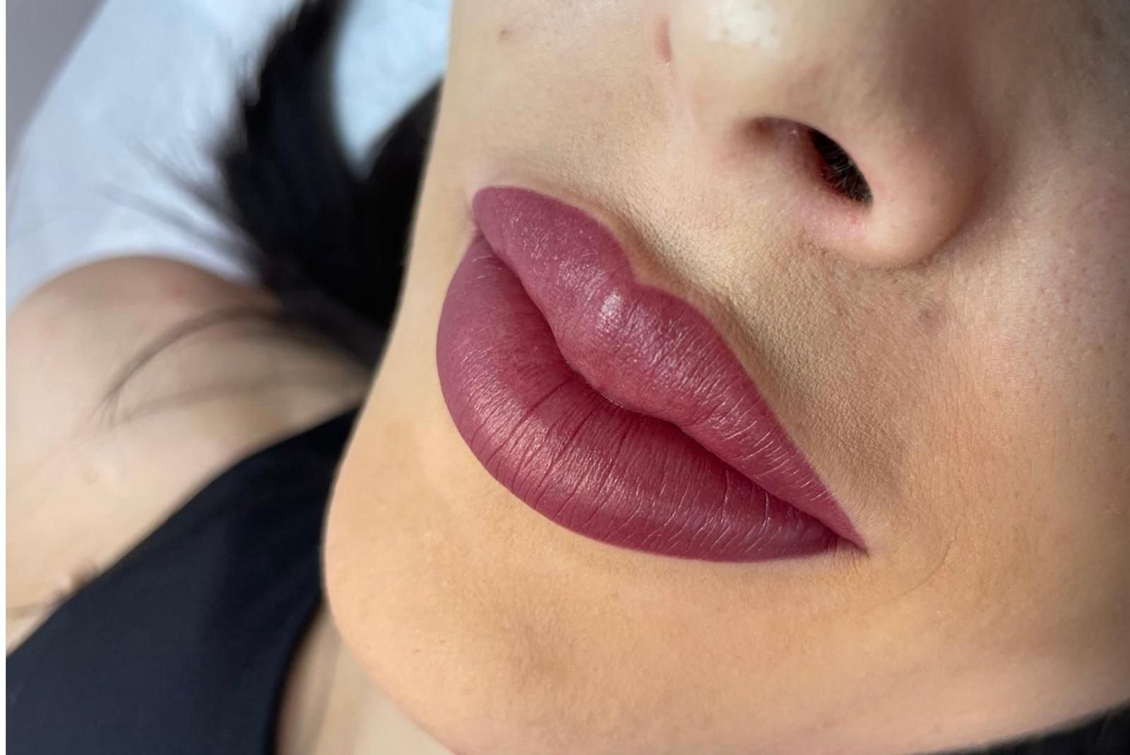 Close-up of lips with matte plum lipstick and a black choker near the neck