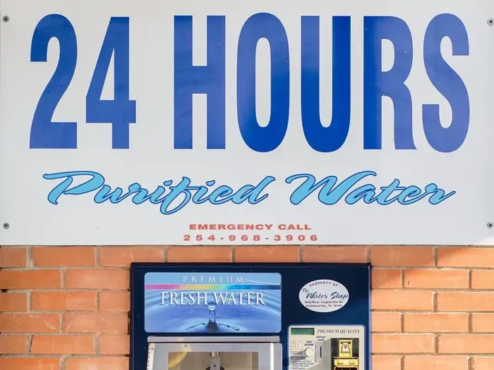 A 24 hour water vending machine on a brick wall