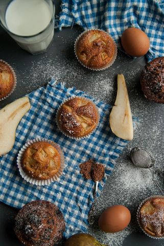 A table topped with muffins , eggs , and a glass of milk.