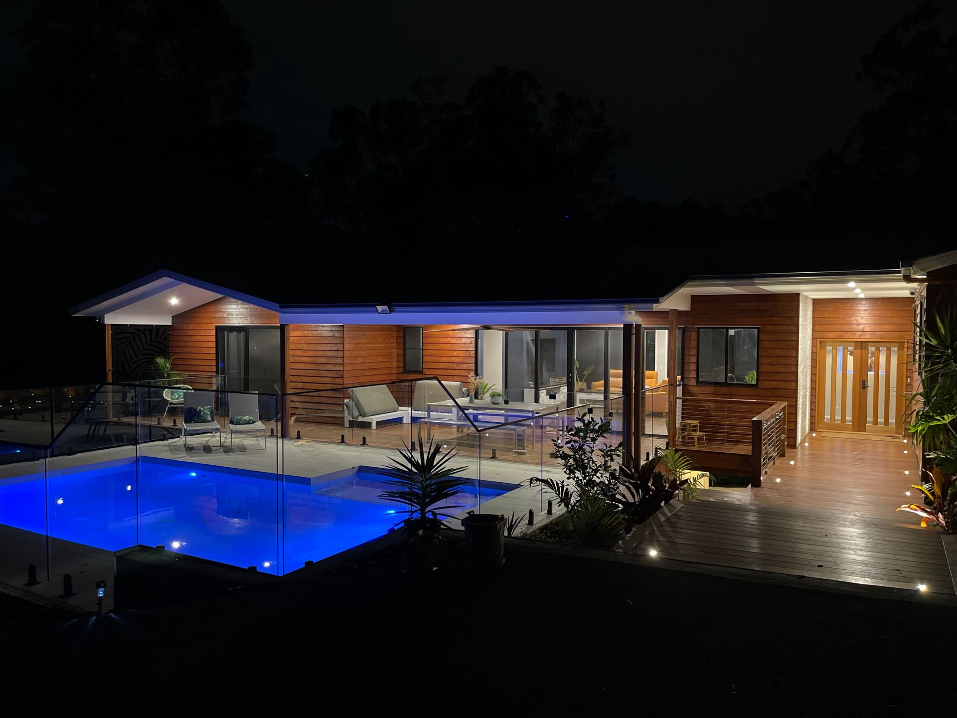 A house with a swimming pool in front of it at night.