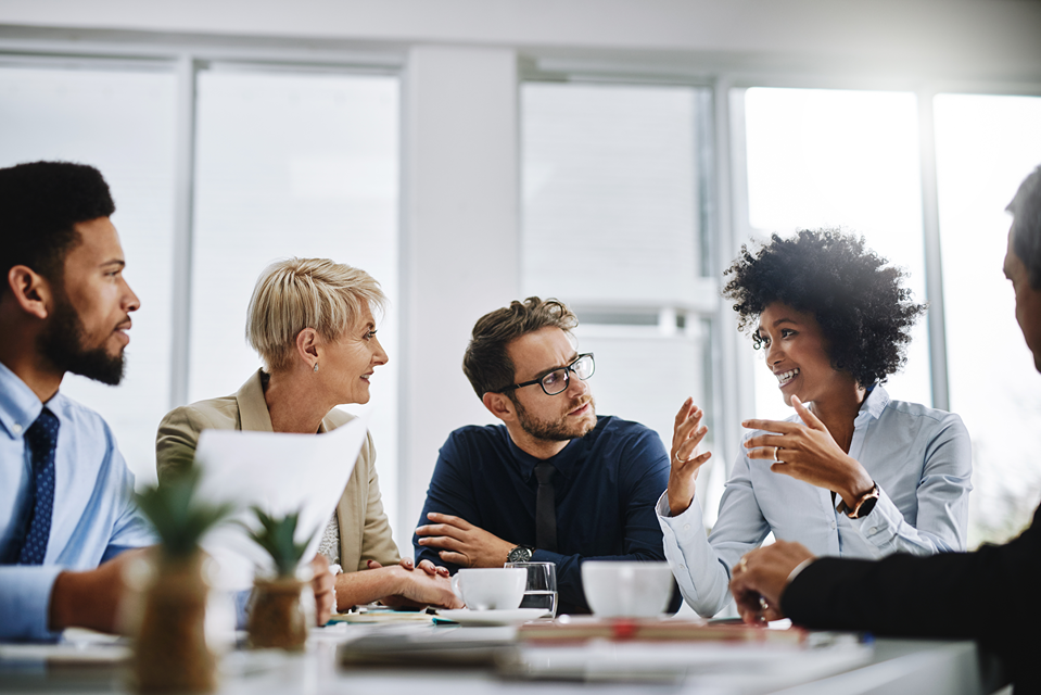 A group of people are sitting around a table having a meeting.