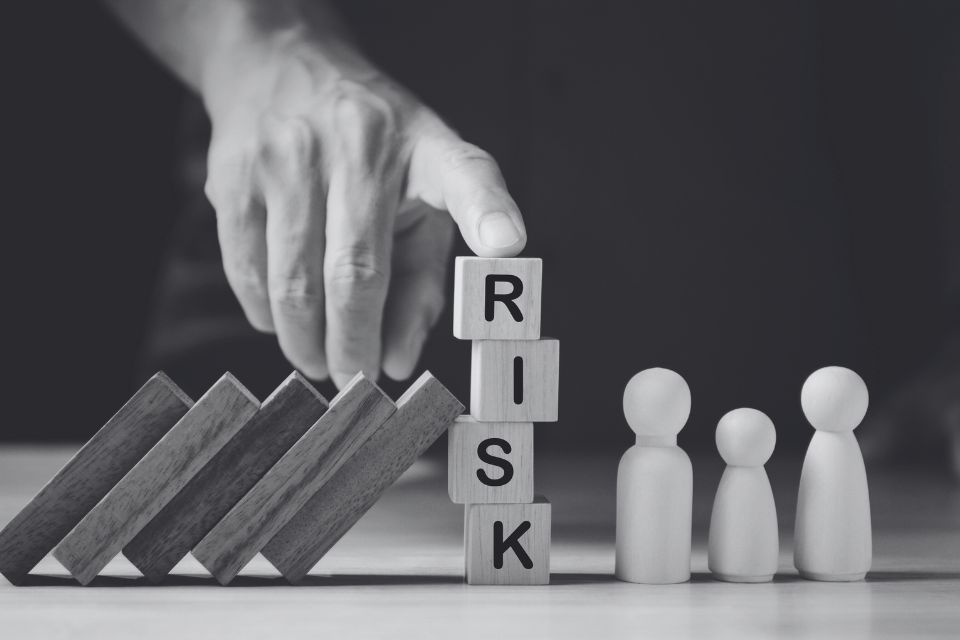 A person is stacking wooden blocks with the word risk written on them.