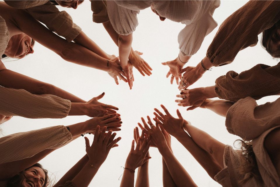 A group of people are putting their hands together in a circle.