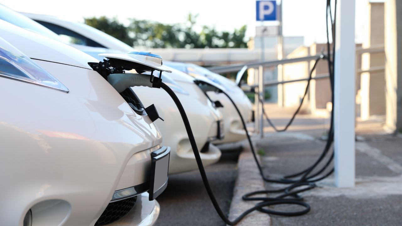 A row of electric cars are being charged at a charging station.