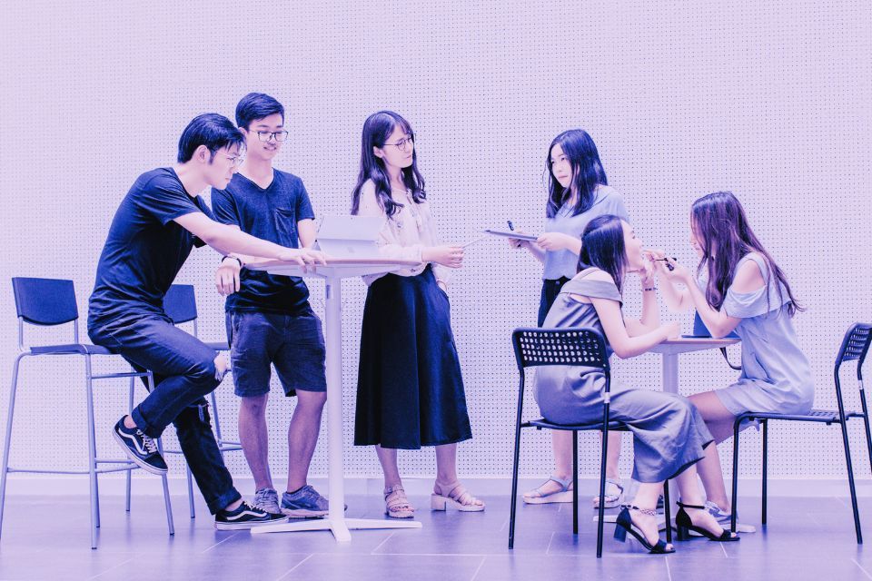 A group of people are sitting around a table talking to each other.