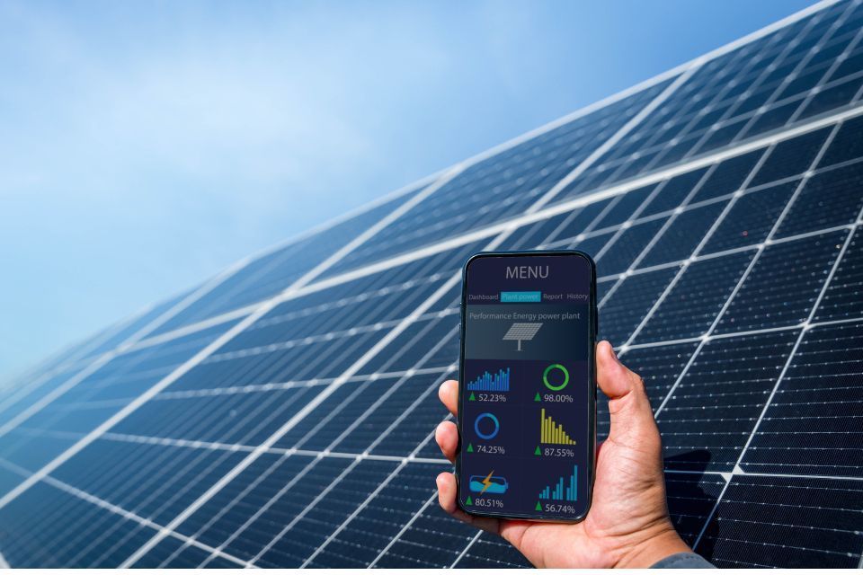 A person is holding a cell phone in front of a solar panel.