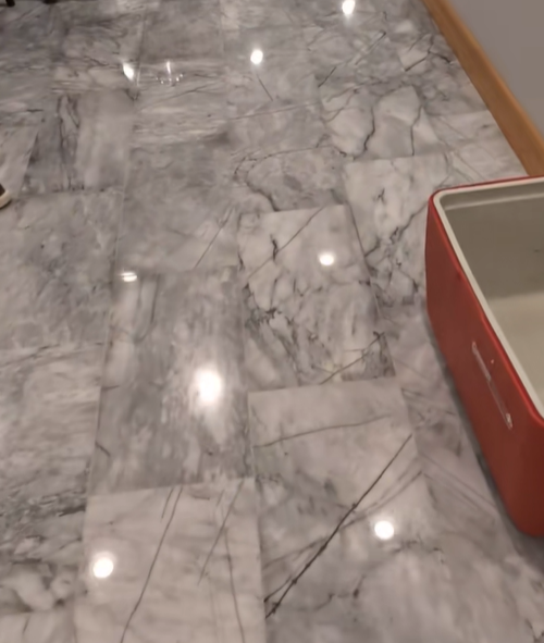 Marble tiled floor with a red container on the right.