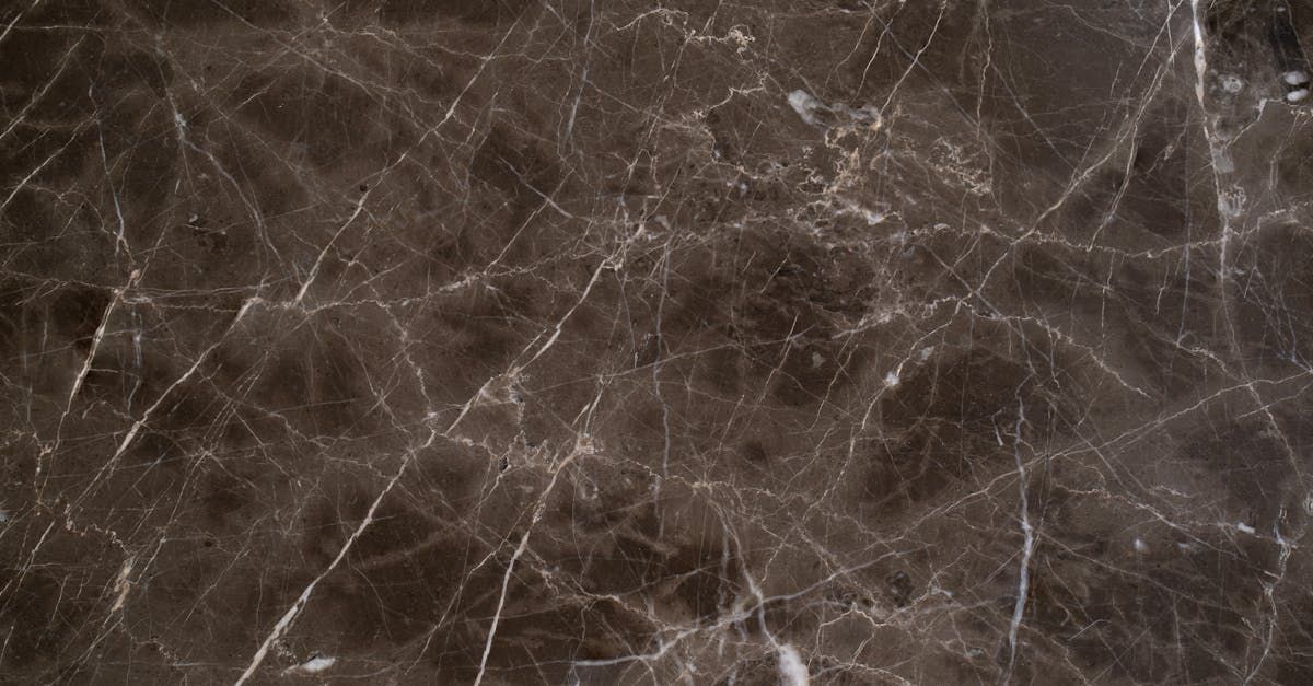 Hand applying white caulk between dark gray tiles.