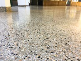 Polished terrazzo floor in a building, featuring speckled gray, white, and black aggregate.