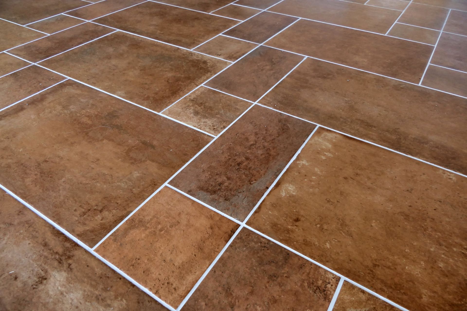 Brown tiled floor with white grout in a rectangular pattern.