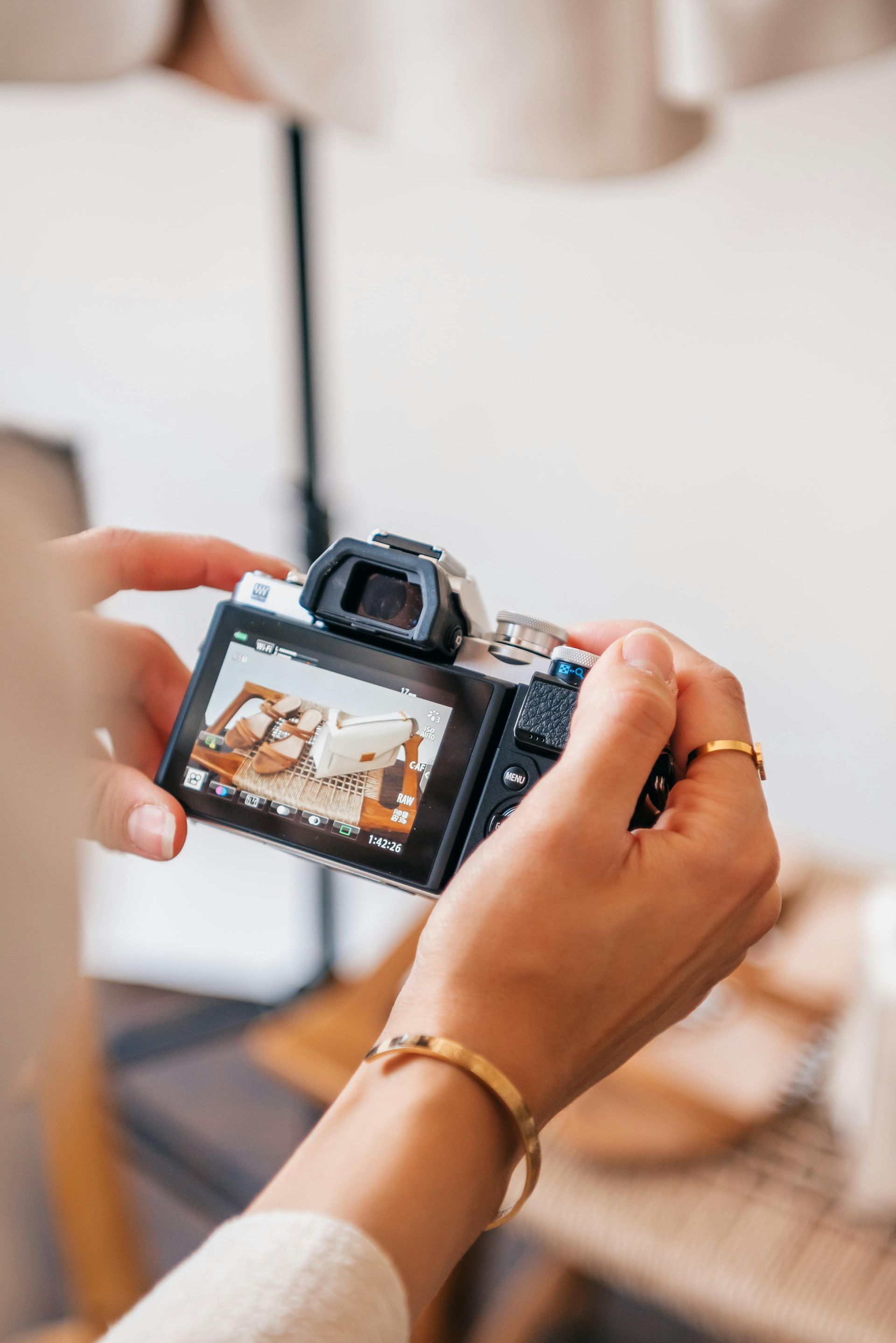 Person holding a camera, focused on the camera screen with a photo of food.
