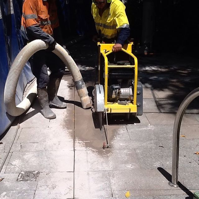 A man is using a yellow machine to cut concrete